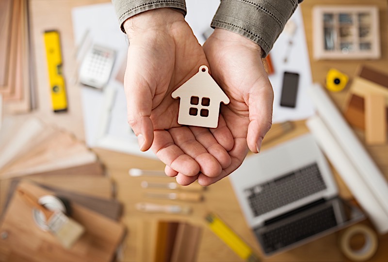 A Hand-holding real estate kit in a construction planning background.