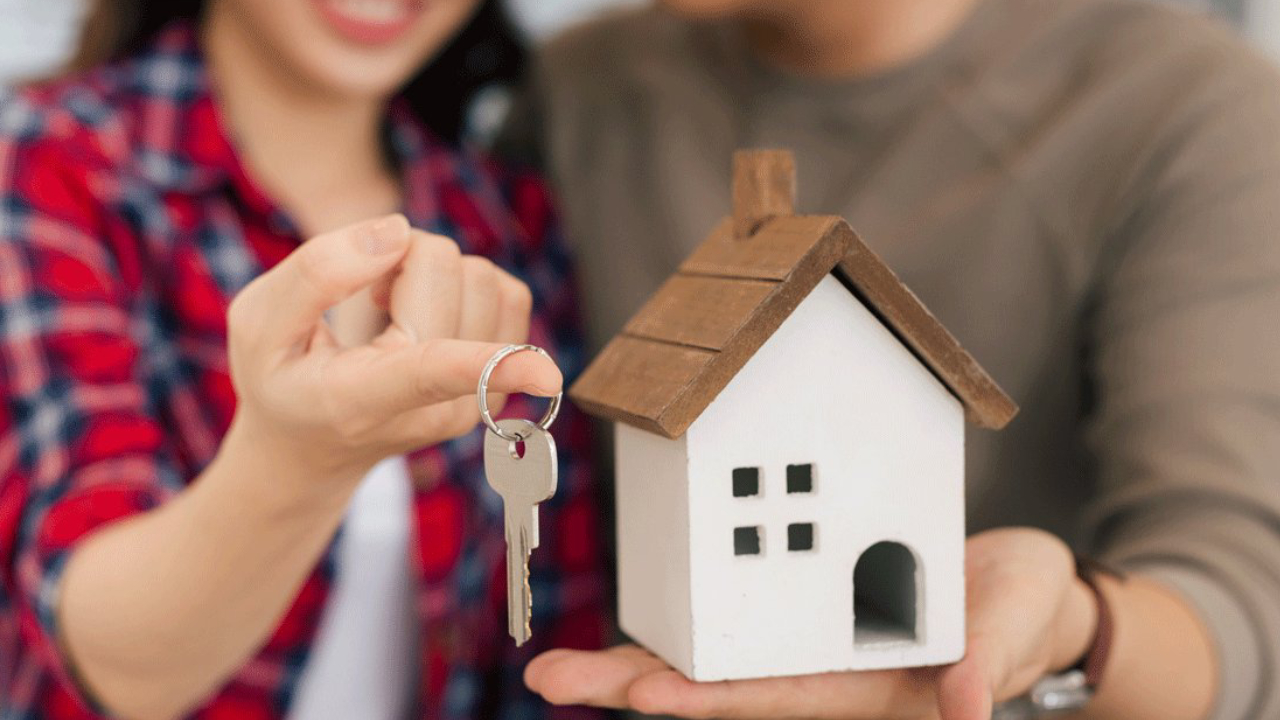 A Couple holding the keey and real estate kit which resembles the approval.